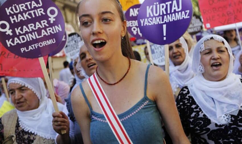 Women hold signs as they take part in a demonstration against government plans t