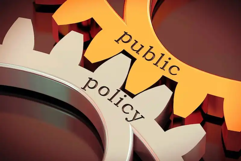 Two cogs fitting together on which public policy is written